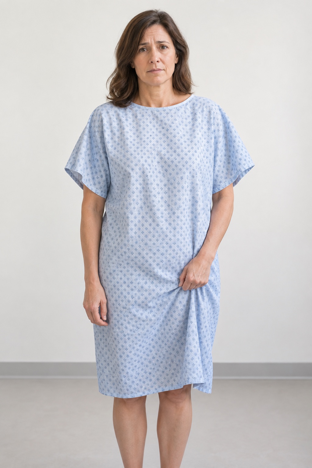 Front view of a woman adjusting a thin traditional patient gown